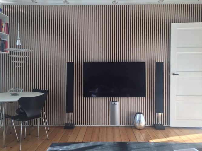 Akustik Holzpaneelwand mit Fernseher und B&O Lautsprechern.