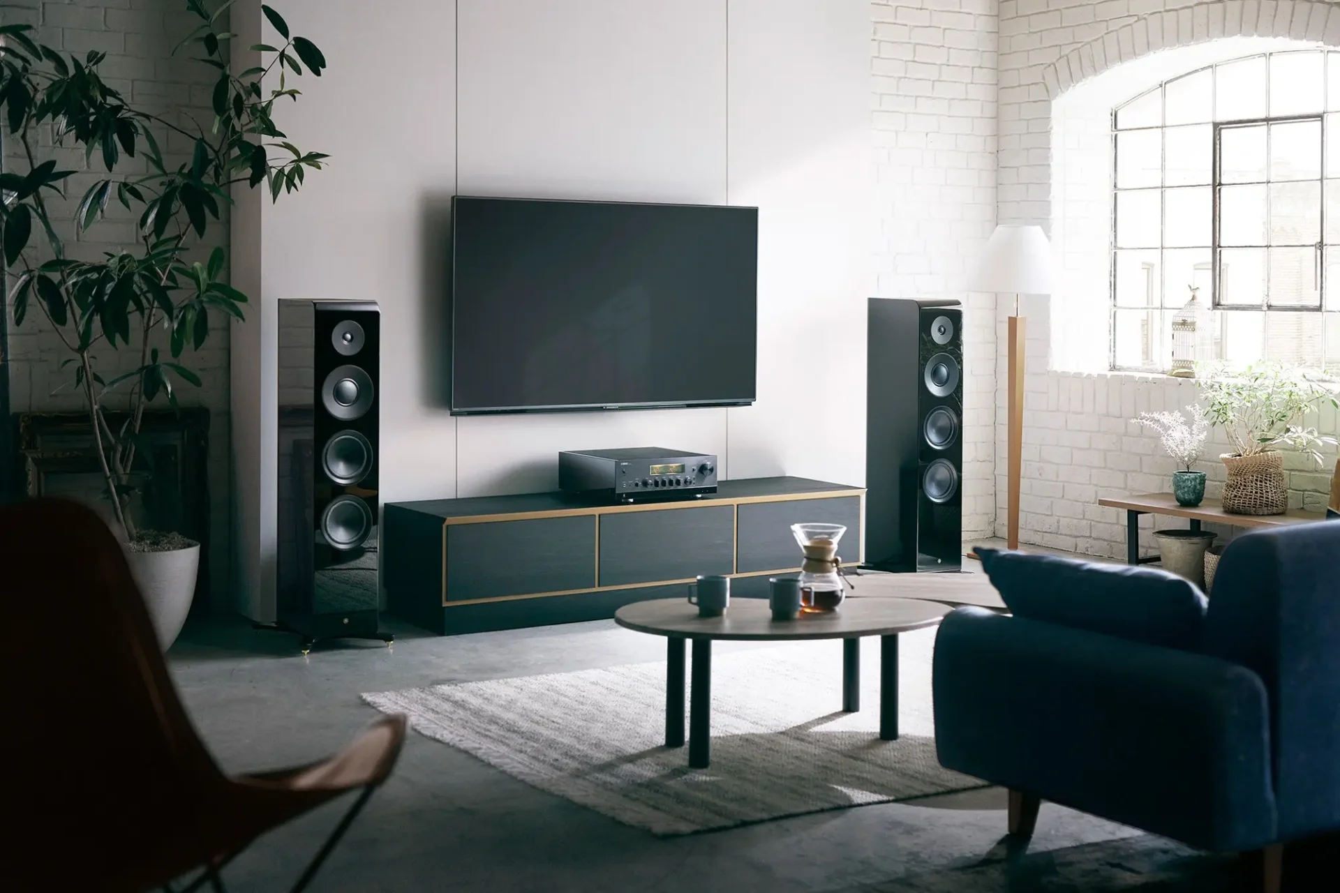 Yamaha R-N2000A in einem Wohnzimmer. Der Stereo-Verstärker mit HDMI dient auch als Netzwerk Receiver. Hier steht das schwarze Modell auf einem dunklen Lowboard in einem minimalistischen Wohnraum.