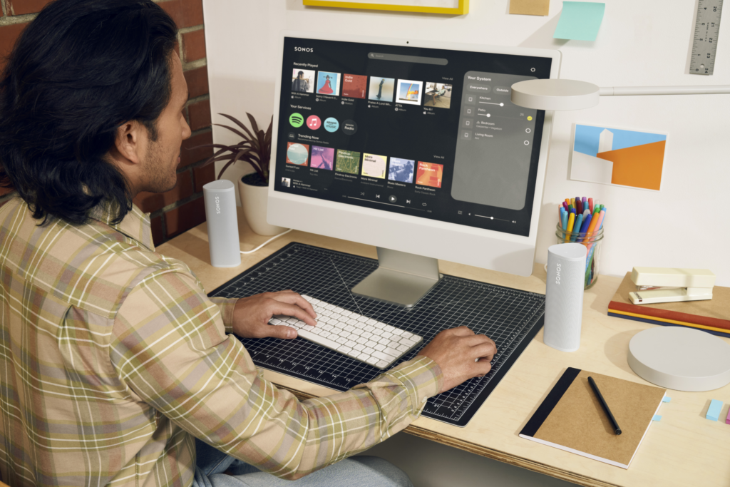 Die neue Sonos S2 Webapp für den Desktop wird von einem jungen man ein einem modernen Home Office Setup bedient.