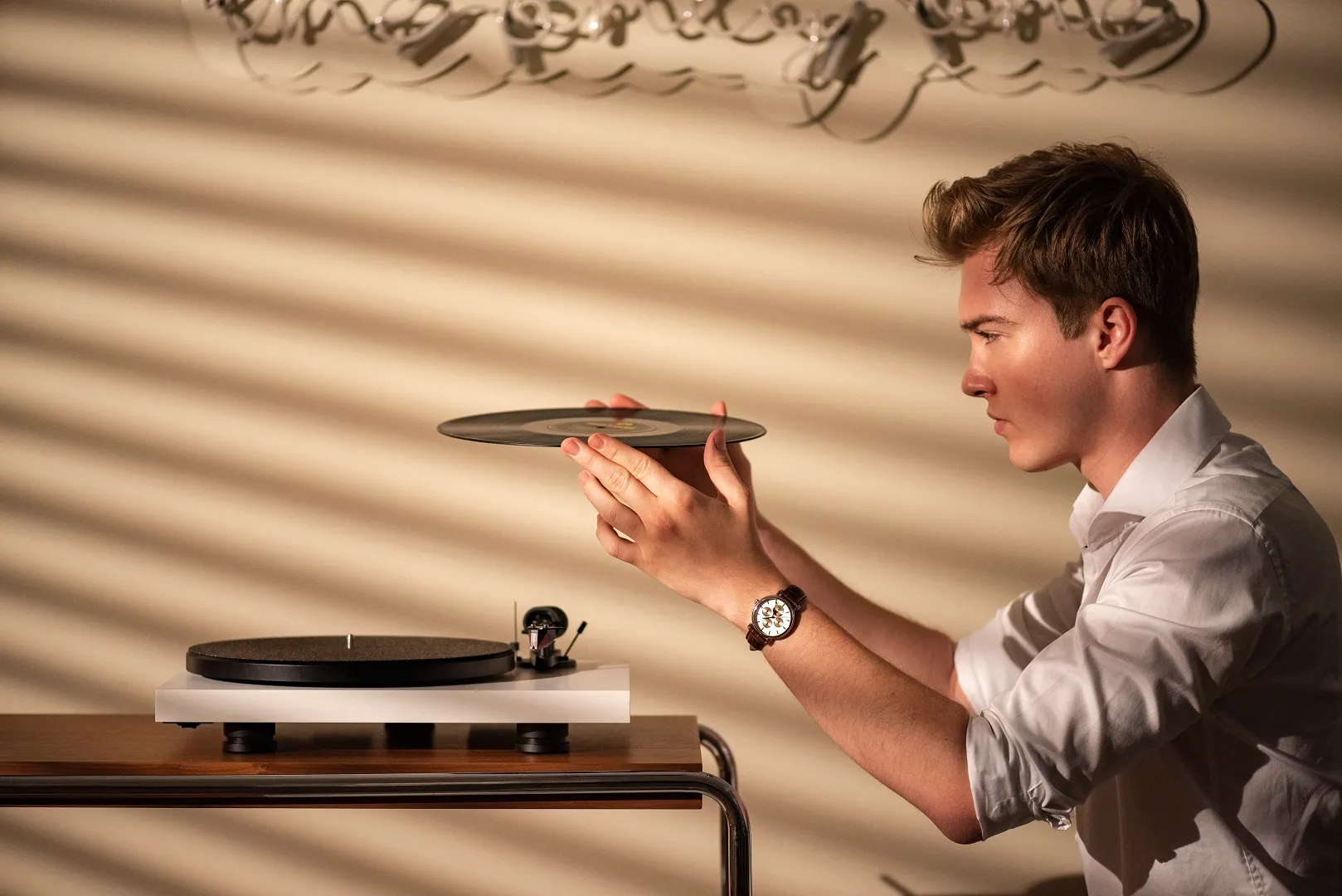 Ein Mann legt bedächtig eine Platte auf einen minimalistischen Plattenspieler.