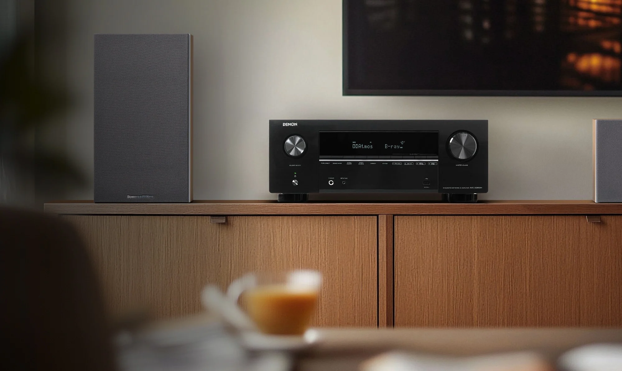 Das Bild zeigt den Denon AVR-X2850H von vorne auf einem Möbel.