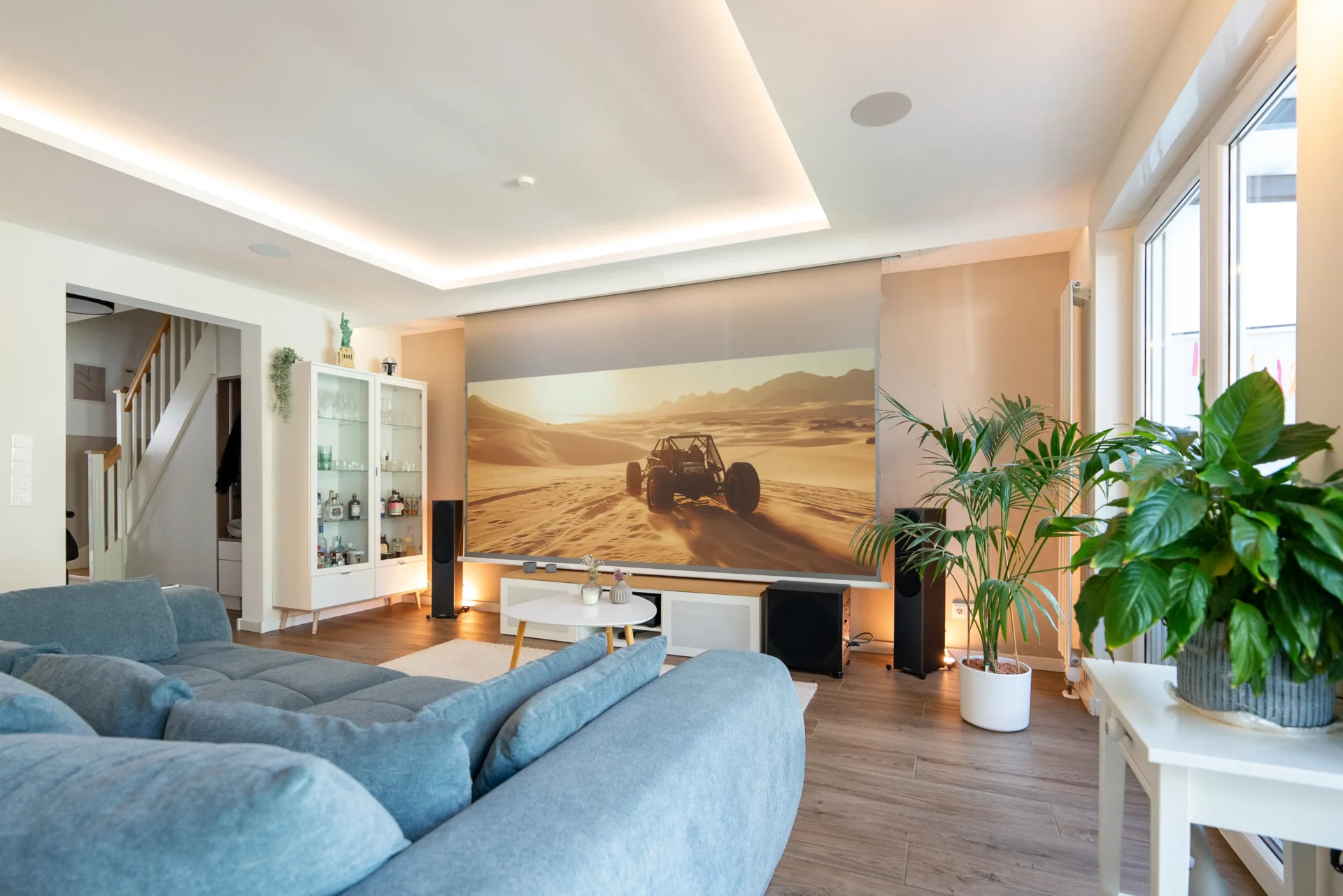 Modernes White Cinema Heimkino im Wohnzimmer mit 135 Zoll Leinwand, Offroad-Szene in der Wüste, stilvolles Design vom AVITECT Studio Aachen.