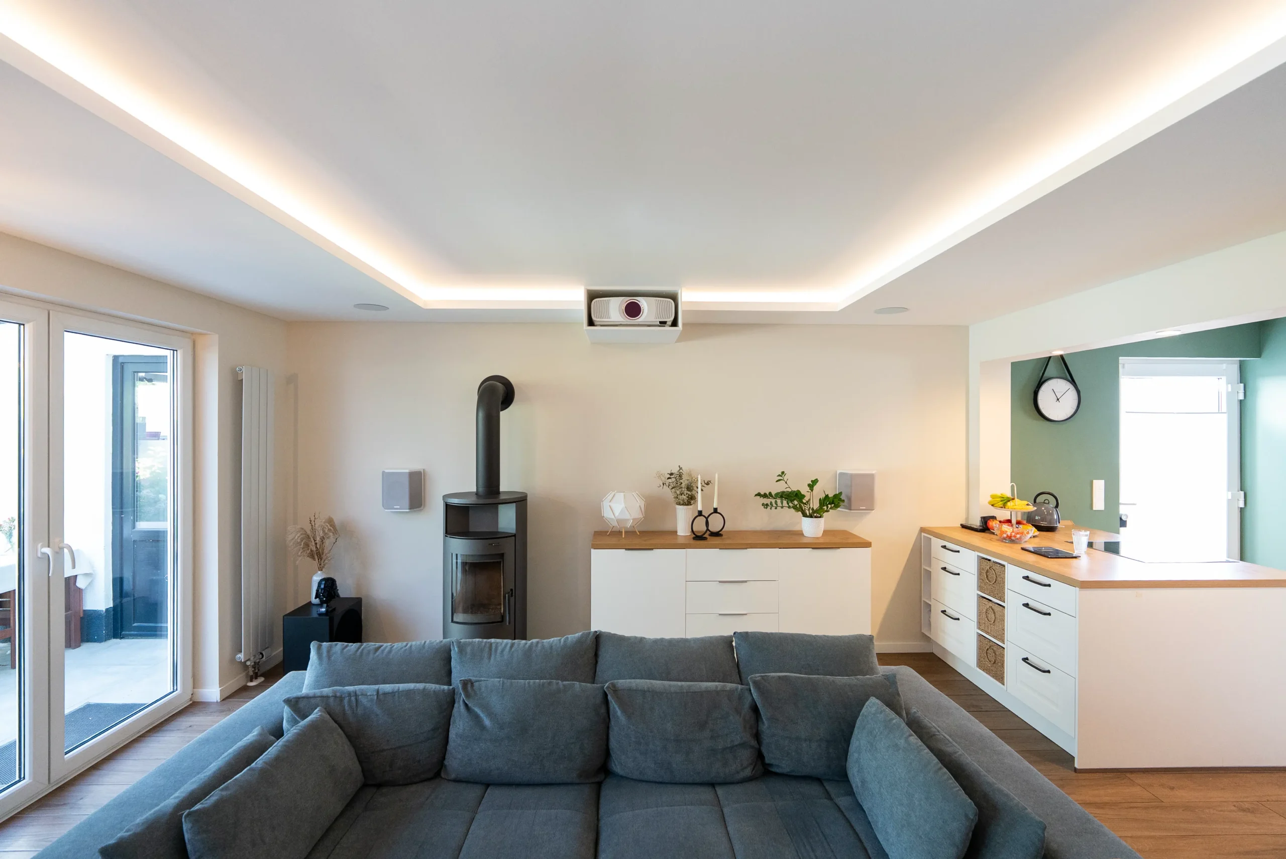 White Cinema Heimkino Wohnzimmer mit großem Sofa, Kamin und in die Decke integriertem Epson Beamer vom AVITECT Studio Aachen.
