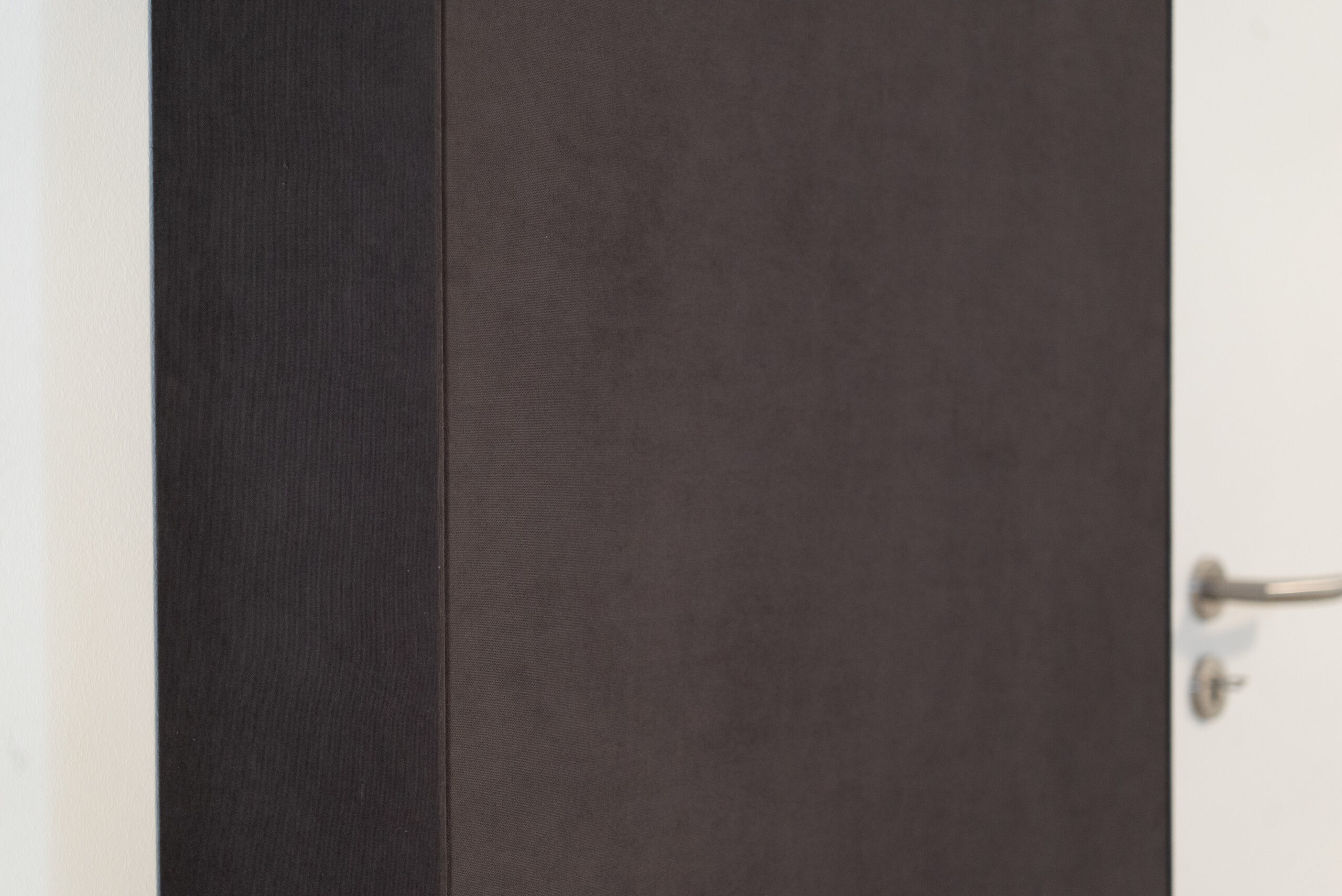 Detailaufnahme einer dunklen Stoffbespannung – elegante Wandverkleidung im Heimkino, umgesetzt vom AVITECT Studio Rhein-Main.