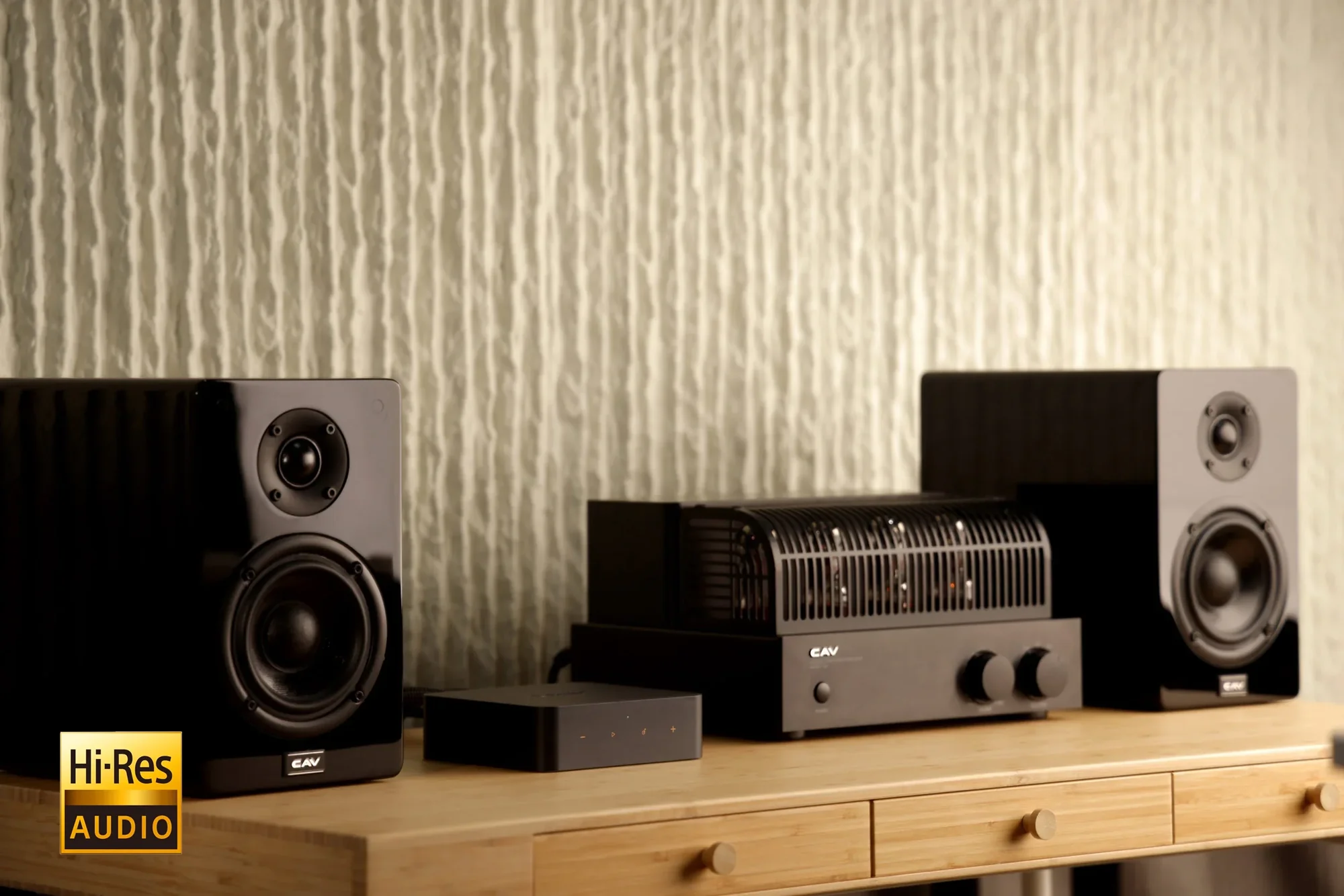 Das BIld zeigt den WiiM pro Plus streamer gemeinsam mit der Fernbedienung auf einer Oberfläche in einem HiFi-Setup mit Lautsprechern