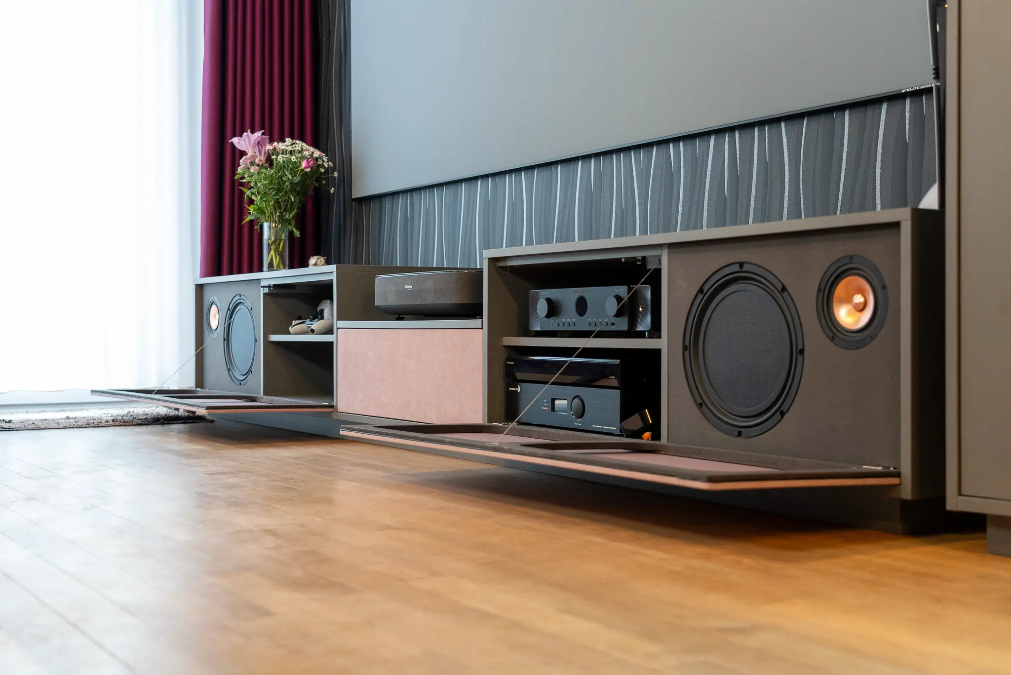 Geöffnetes maßgefertigtes Heimkino-Möbel zeigt Verstärker, Zuspieler und Subwoofer – aufgeräumte Techniklösung für das White Cinema im Wohnbereich.