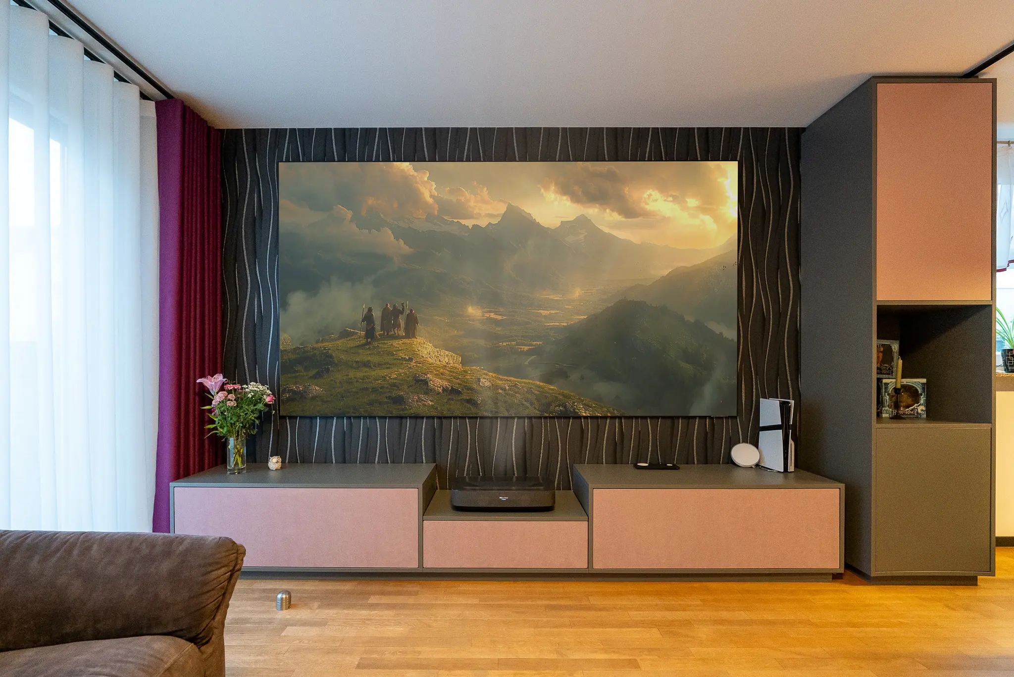 Helles White Cinema mit großem Bergpanorama auf der Leinwand, Laser TV im Lowboard und roséfarbenen Fronten – zeigt die Bildwirkung im Wohnzimmer bei Tageslicht.