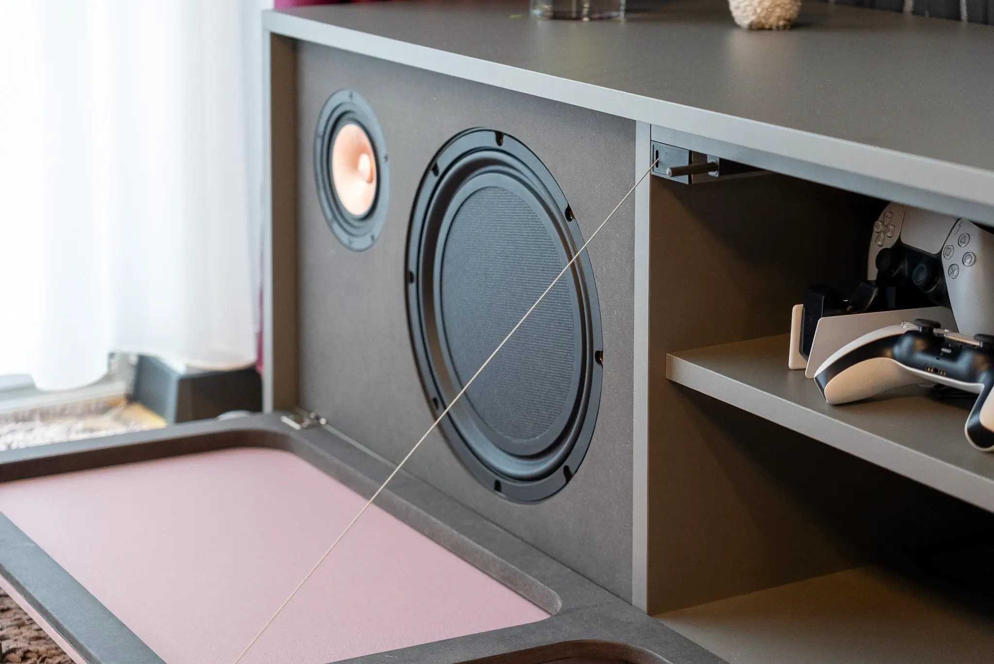 Detailaufnahme von Subwoofer und Lautsprecher im Sideboard des White Cinema: unsichtbar hinter Stoffklappen, akustisch perfekt in den Wohnraum integriert.