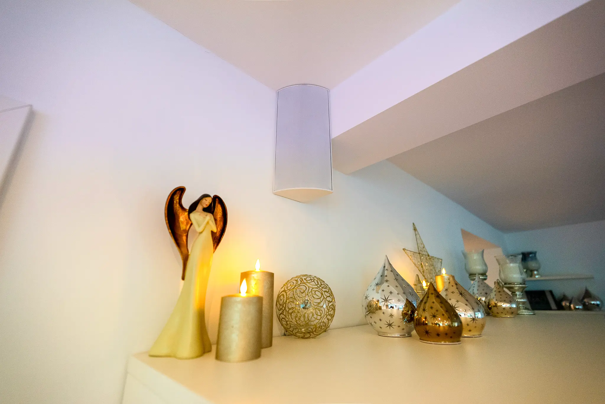 Dezent installierter, weißer Surround-Lautsprecher (Cornered Audio) in der Zimmerecke, harmonisch integriert oberhalb der Dekoration.