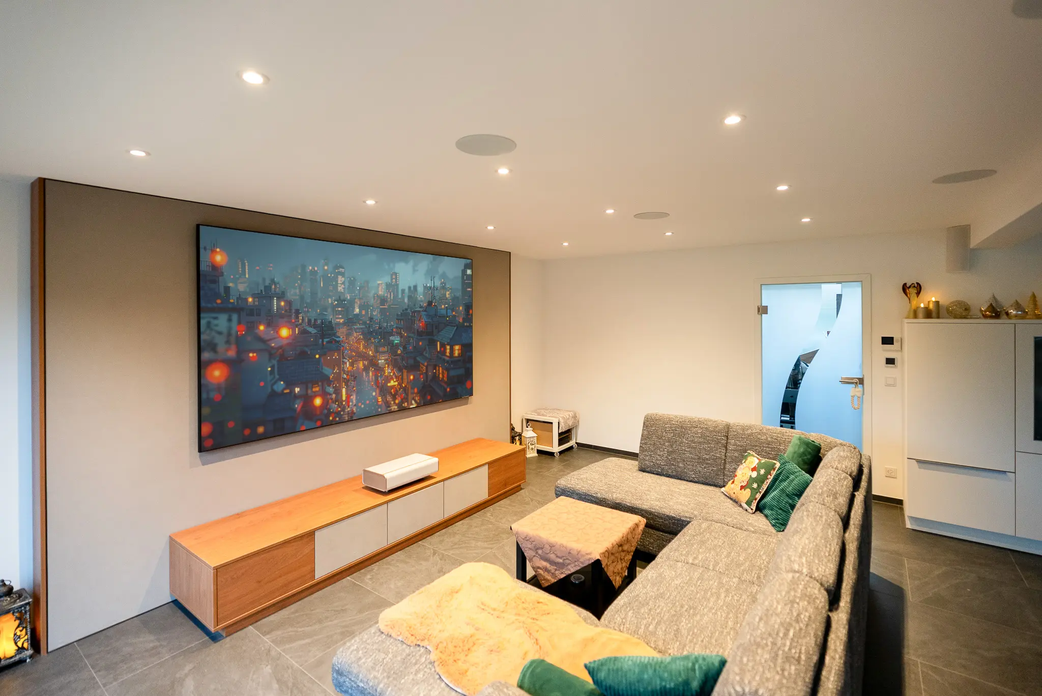 Blick in das offene Wohnzimmer: Das Heimkino-Setup mit Soundwall und Lowboard fügt sich perfekt in das helle Raumkonzept mit Flurzugang ein.