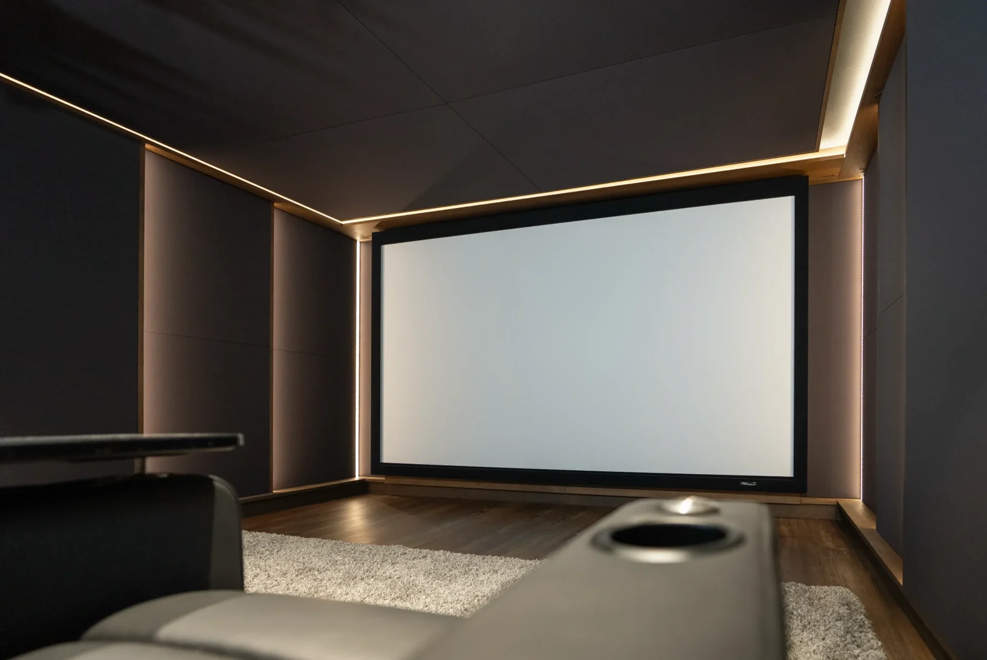 Ausgeschaltete Projektionsleinwand mit warmem LED-Randlicht im fertigen Heimkino Bochum.