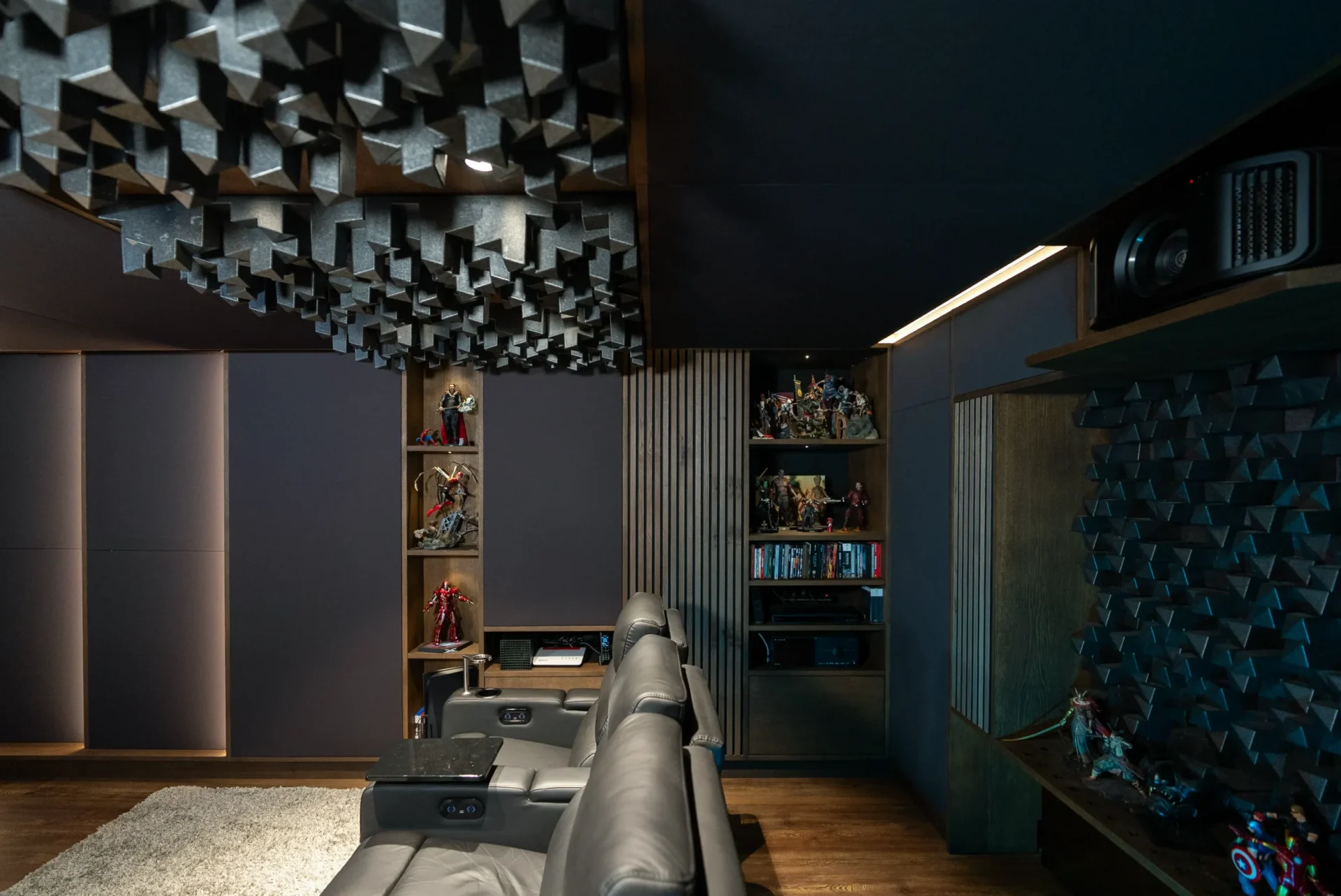 Kinosessel unter Skyline-Diffusoren an Decke und Wand mit Figurenregalen im AVITECT Heimkino Bochum.