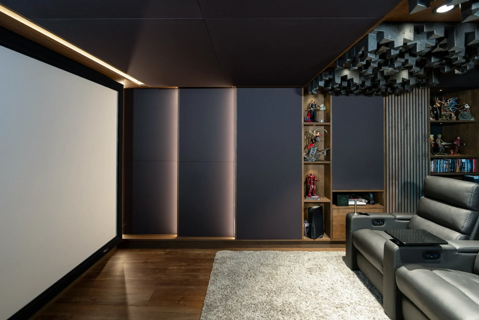 Seitenansicht mit Leinwand, LED-Akzentlicht und beleuchteter Figurensammlung im Heimkino Bochum.
