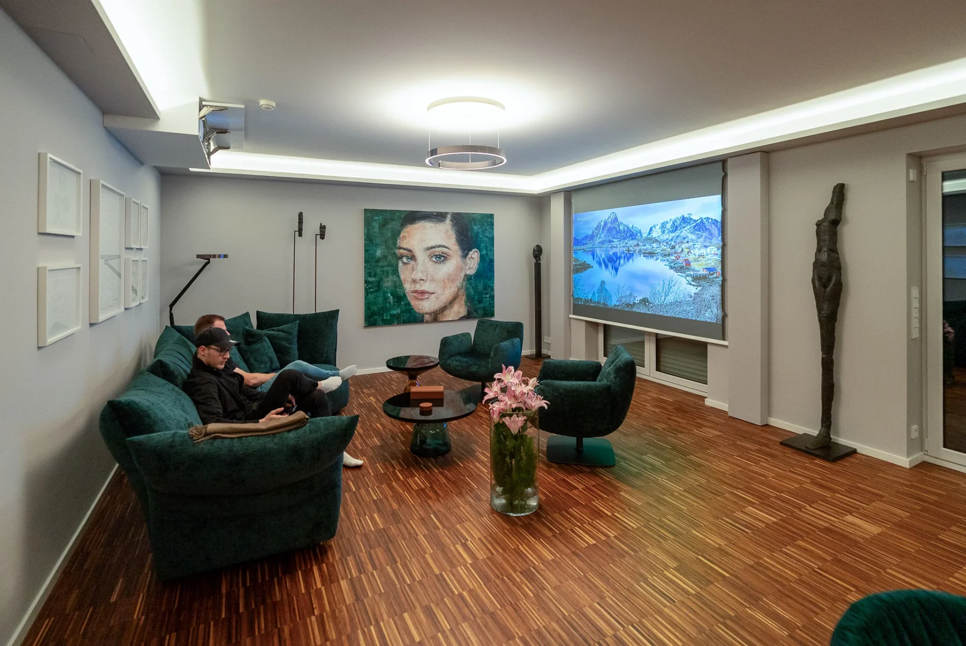 Kinobetrieb mit Landschaftsbild auf der Leinwand, grüner Sitzgruppe und indirekter Lichtvoute im Referenzprojekt Rhein-Main.