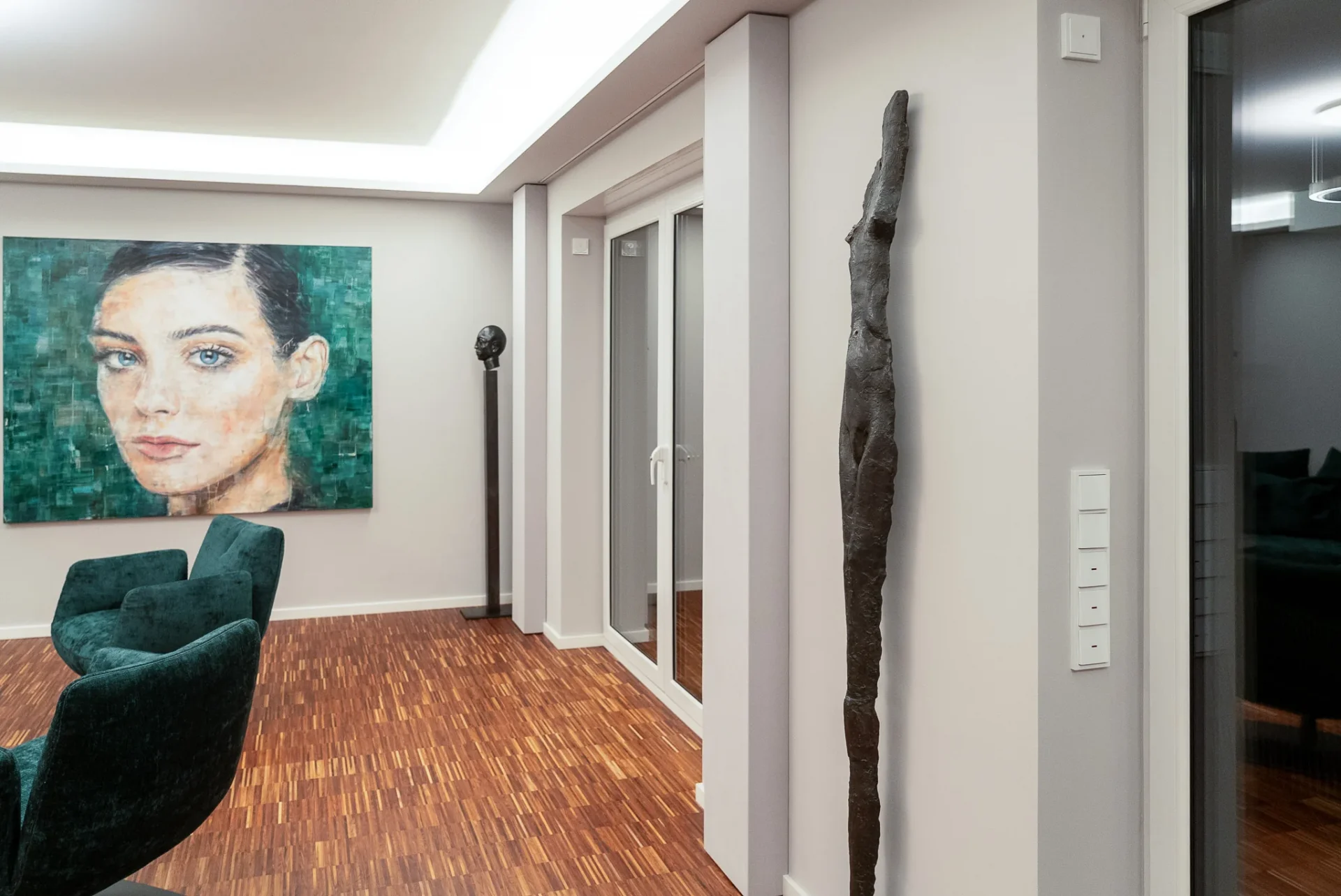 Großformatiges Porträt, Skulptur und grüne Samt-Sessel vor Glastür im Wohnbereich des Referenzprojekts Rhein-Main.