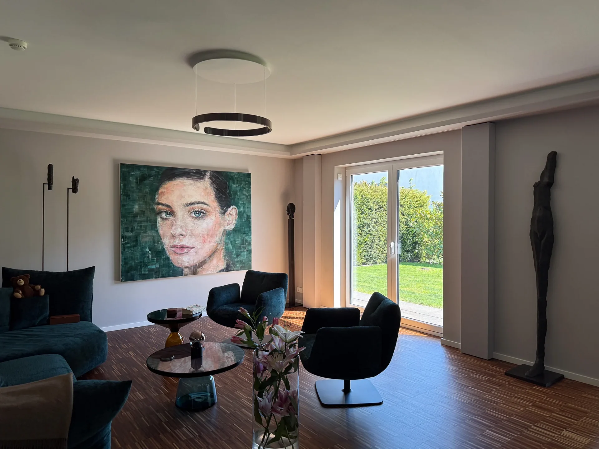 Wohnzimmer mit Samt-Möbeln, großem Porträt und Glastür zum Garten im White-Cinema-Referenzprojekt Rhein-Main.