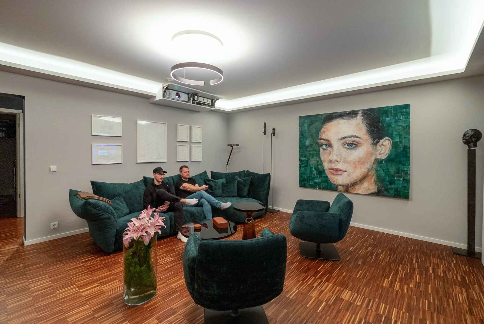 Rückansicht der Lounge mit Projektor an der Decke, Kunstwerk und Samt-Sitzgruppe im Referenzprojekt Rhein-Main.
